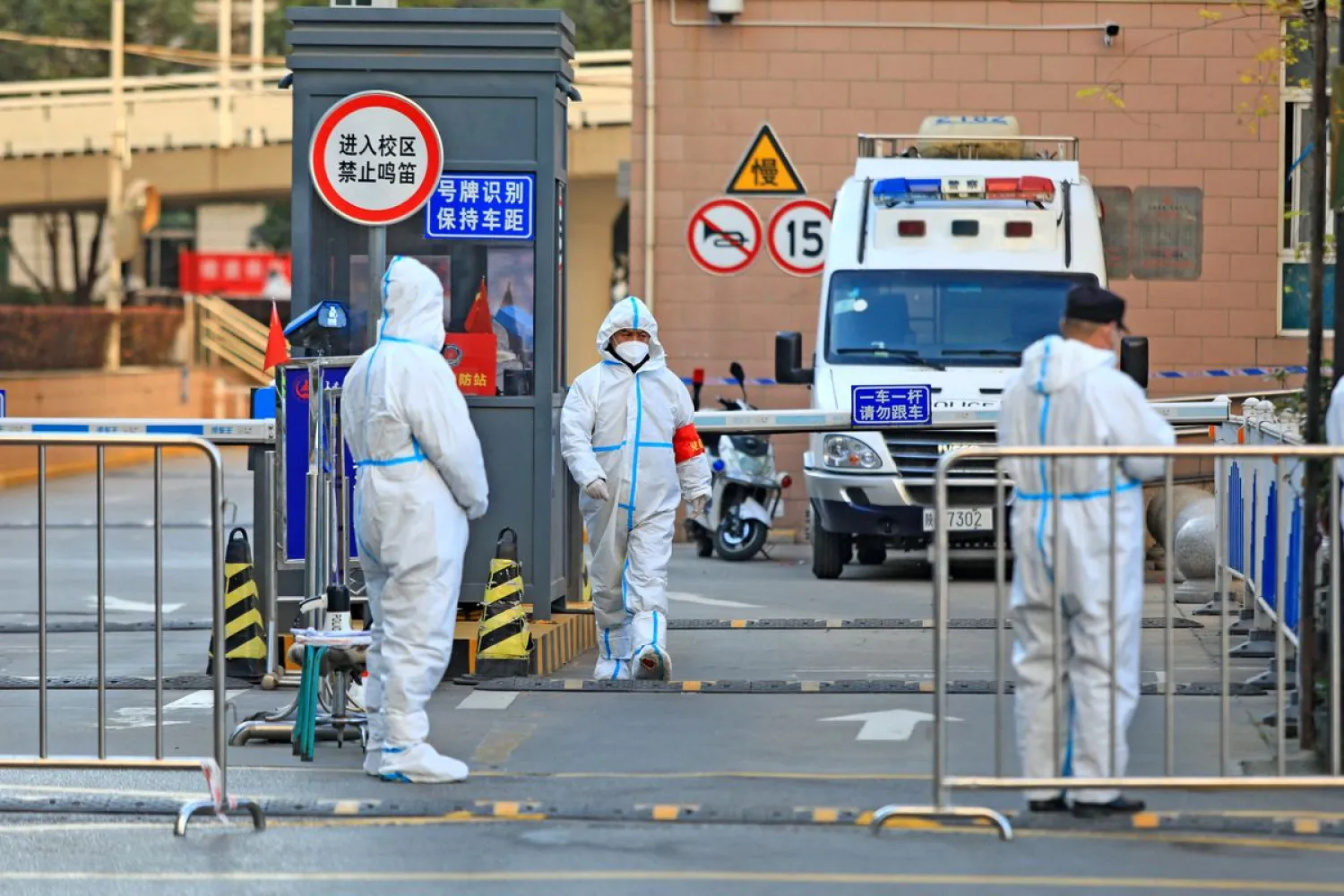 Workers in protective suits stand at an entrance to a university's residential area under lockdown following the coronavirus disease (COVID-19) outbreak in Xian, Shaanxi province, China December 20, 2021. China Daily via REUTERS