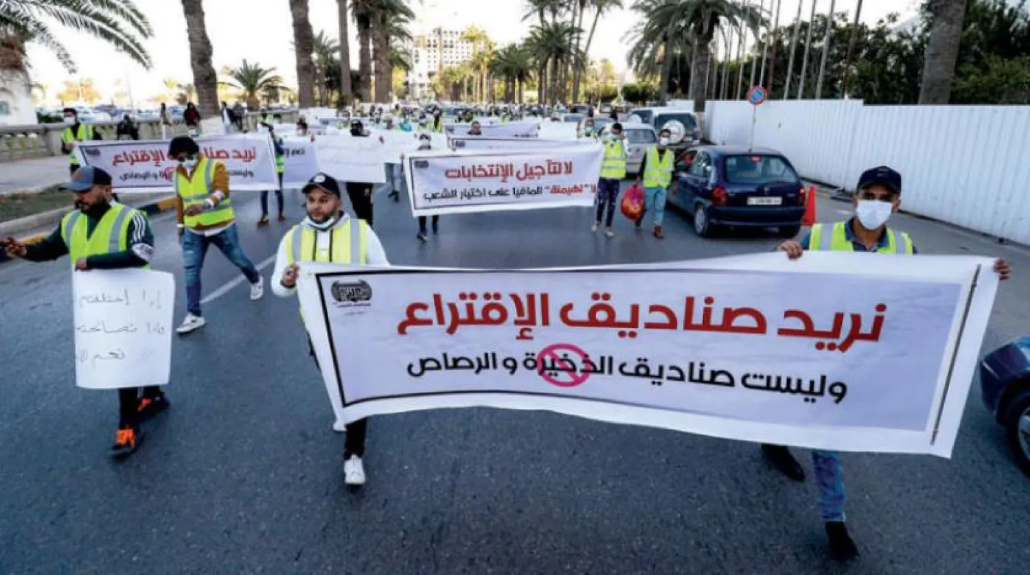 Libyalılar seçimlerin ertelenmesini protesto için başkent Trablus şehir merkezinde gösteri düzenledi (AFP)