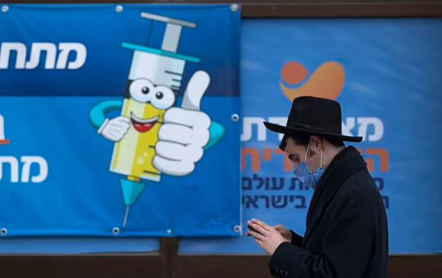 An Ultra-Orthodox Jewish man walks past a coronavirus vaccination center, in Jerusalem, Wednesday, Dec. 22, 2021. (AP Photo/Oded Balilty)

