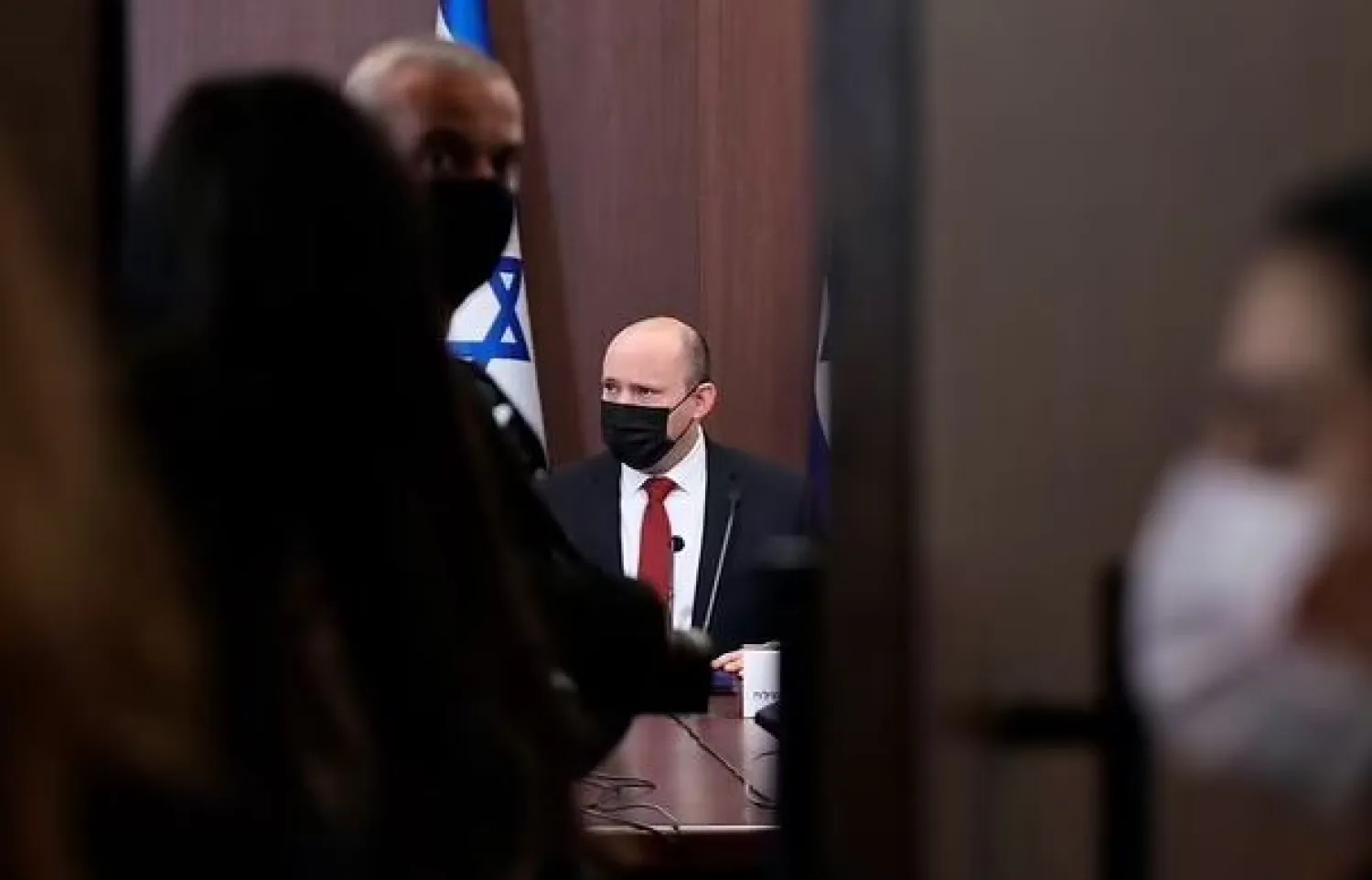 Israeli Prime Minister Naftali Bennett, rear and wearing a face mask, attends during a cabinet meeting at the prime minister's office in Jerusalem, Israel, Sunday, Dec. 19, 2021. (Abir Sultan/Pool Photo via AP)

