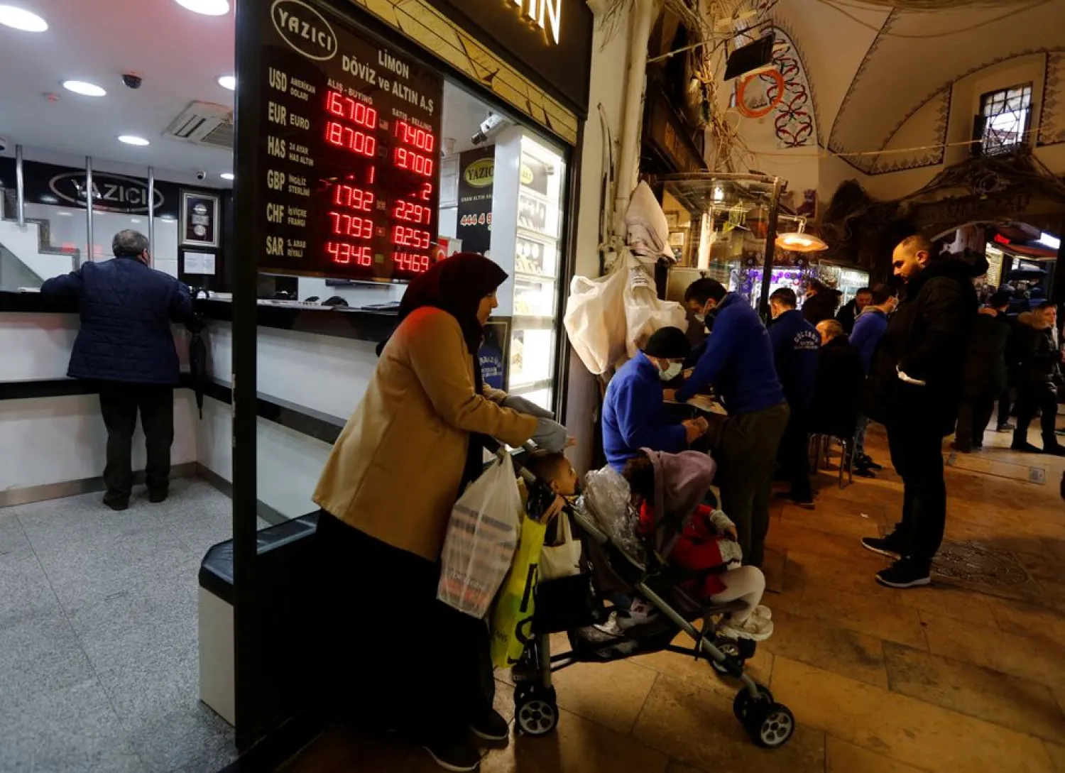 A woman and her baby stand in front of an exchange office in Istanbul, Turkey December 17, 2021. REUTERS/Dilara Senkaya

