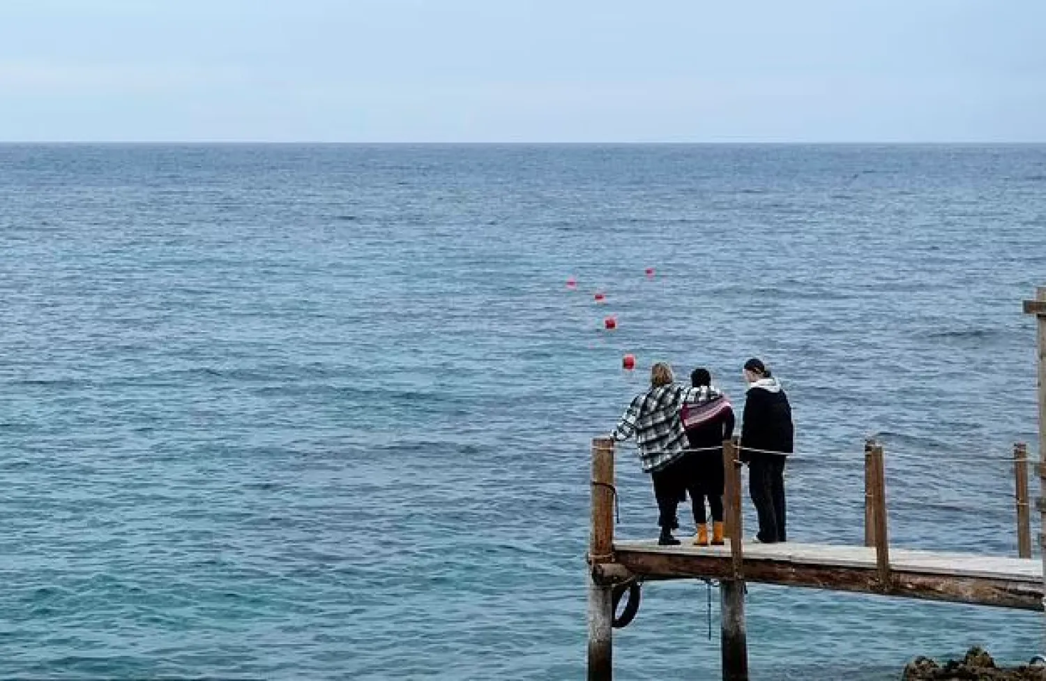 Nadine Kalache Maalouf, center, Celine Elbacha and Elbacha's daughter Morgane, right, stand on a deck at the seaside in eastern coastal resort of Paralimni, Cyprus, Wednesday, Dec. 22, 2021.  (AP Photo/Petros Karadjias)


