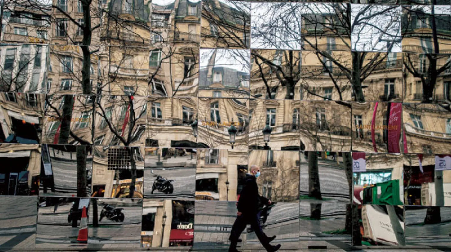 عابر في أحد شوارع باريس يرتدي كمامة بعد أن فرضتها فرنسا مع ارتفاع إصابات كورونا (إ.ب.أ)