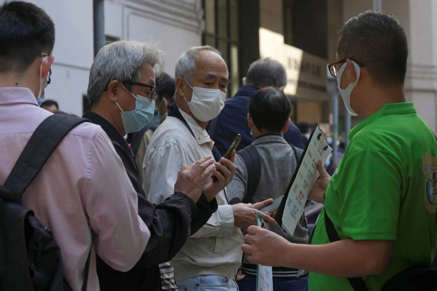 A staff member holds a QR code for the “LeaveHomeSafe” COVID-19 contact-tracing app to people lining up outside a community vaccination center providing Sinovac Biotech's CoronaVac COVID-19 vaccine in Hong Kong, China December 2, 2021. (Reuters)