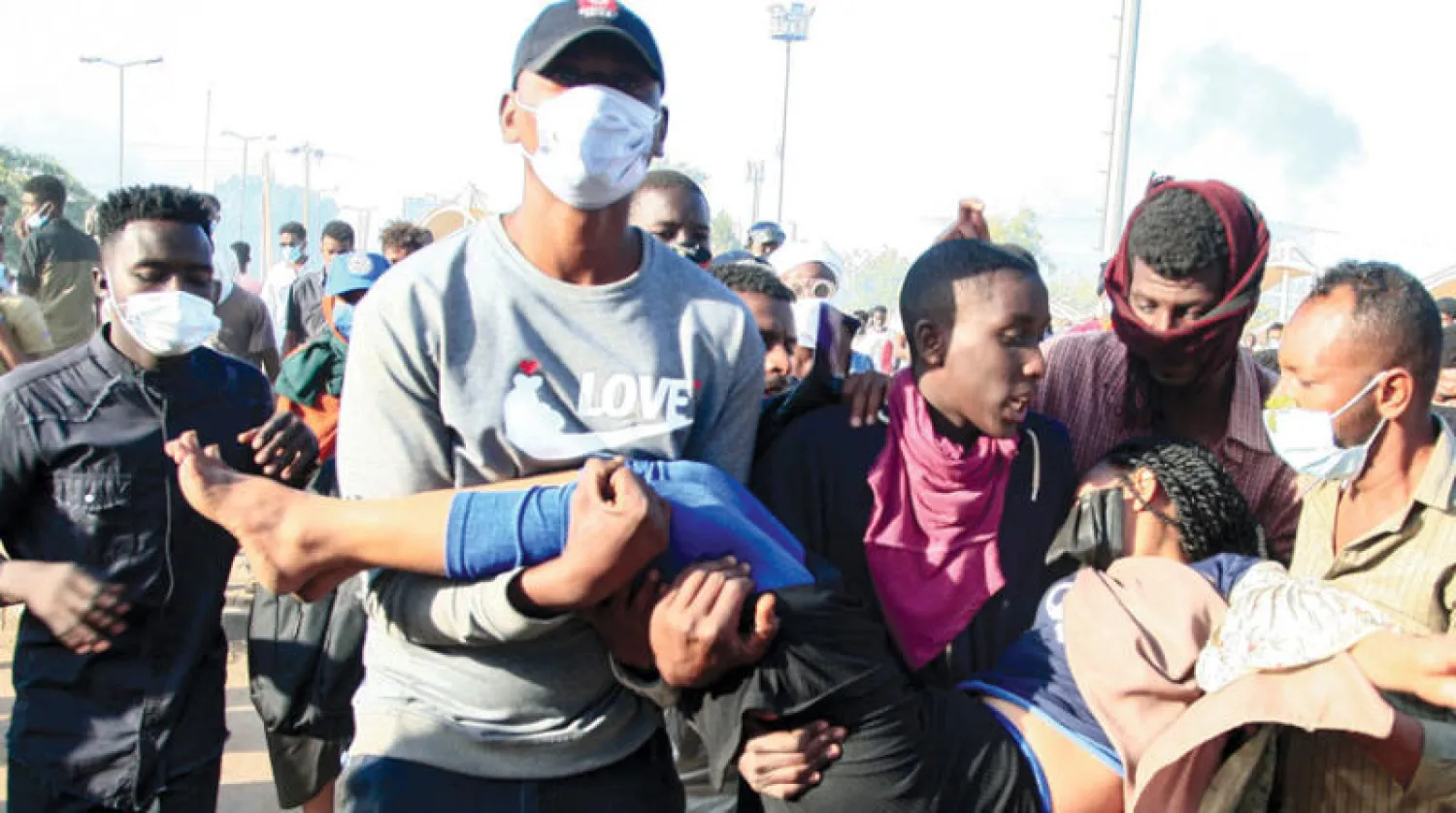 محتجون سودانيون يحملون متظاهرة أصيبت خلال المواجهات مع قوات الأمن في محيط القصر الجمهوري بالخرطوم أمس (أ.ف.ب)