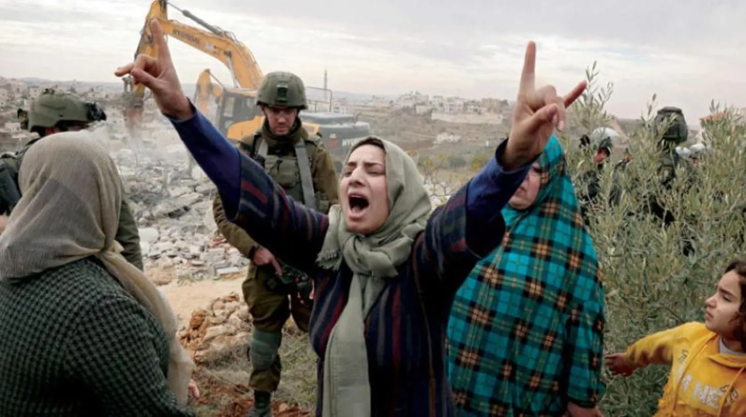 A Palestinian woman cries while Israeli vehicles demolish her house in Hebron in the West Bank on December 28 (AFP)

