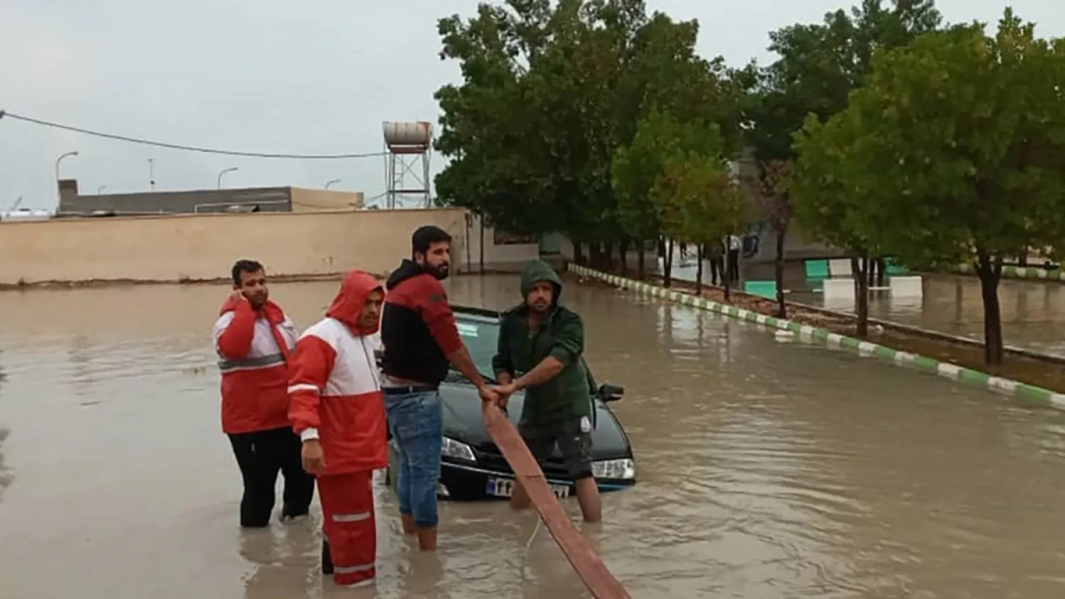 A handout picture made available by the Iranian Red Crescent shows members helping tow a vehicle stuck in floodwaters in Hormozgan Province in the country's south. (AFP)