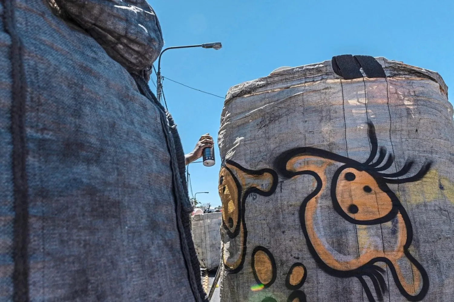Naledi Chai, a graffiti artist, sprays a reclaimer’s trolley. (AFP)