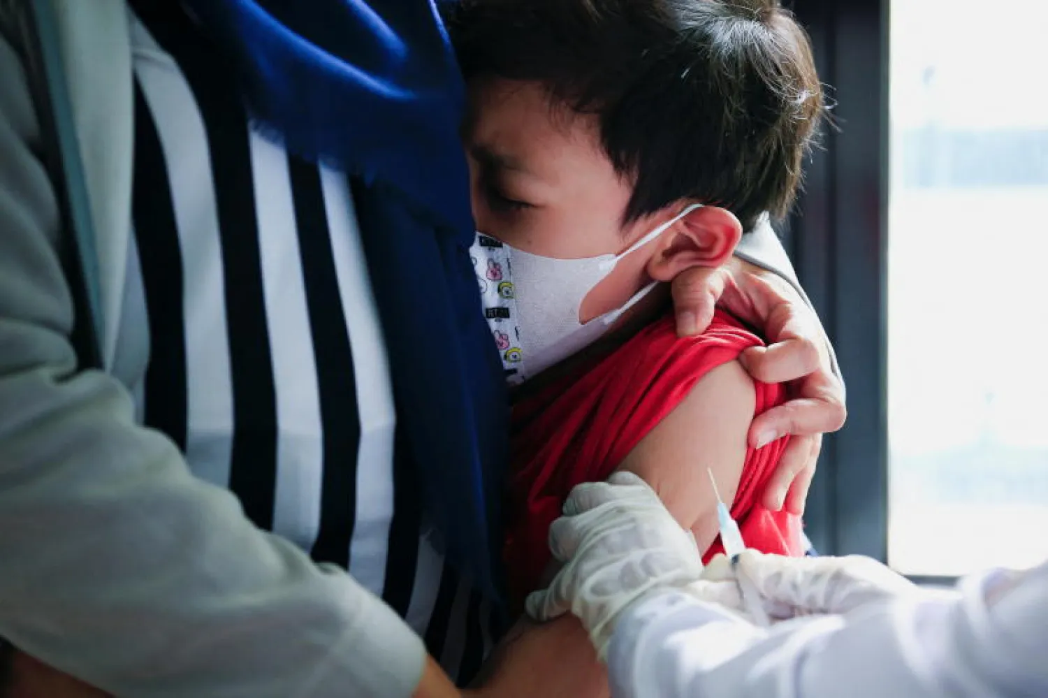 طفل يتلقى جرعة من لقاح مضاد لفيروس كورونا في إندونيسيا (رويترز)