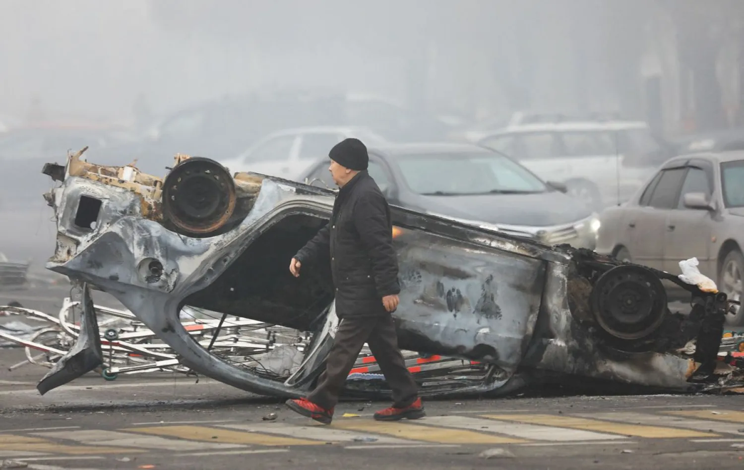 A man walks past a car that was burned during the protests triggered by fuel price increase in Almaty, Kazakhstan January 6, 2022. REUTERS/Pavel Mikheyev