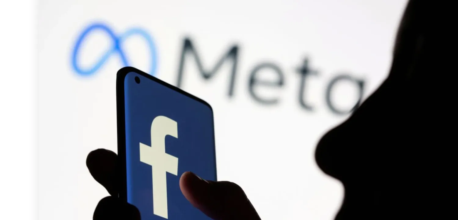 Woman holds smartphone with Facebook logo in front of Facebook's new rebrand logo Meta in this illustration picture taken October 28, 2021. REUTERS/Dado Ruvic