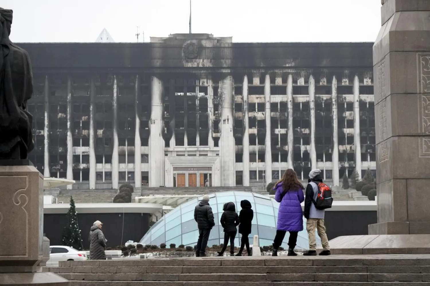People look at the city hall building in the central square blocked by Kazakhstan troops and police in Almaty, Kazakhstan, Tuesday, Jan. 11, 2022. (AP)
