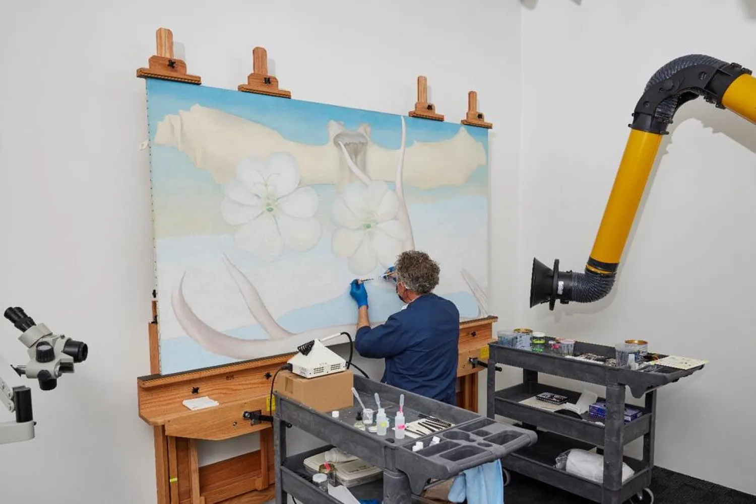 In this photo provided by the Georgia O'Keeffe Museum, Dale Kronkright, head of conservation and preservation at the Georgia O'Keeffe Museum, works on restoring O'Keeffe's painting "Spring," Saturday, Nov. 13, 2021, in Santa Fe, New Mexico. 
