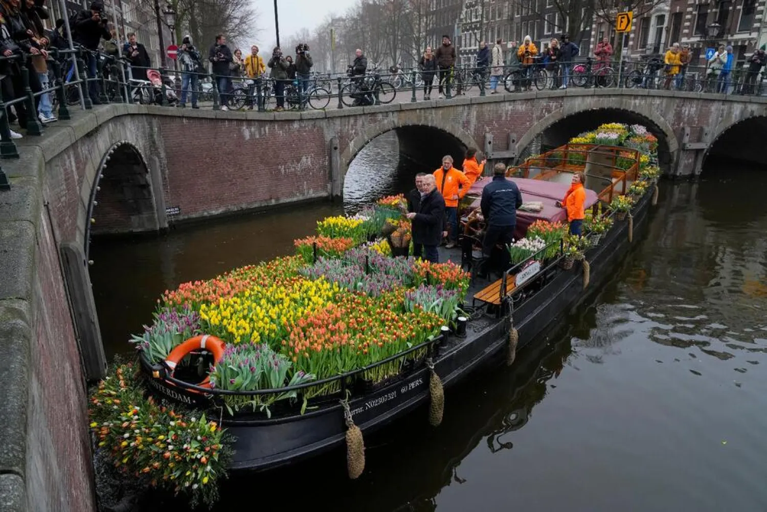 On the day stores in Amsterdam and across the Netherlands cautiously re-opened after weeks of coronavirus lockdown, the Dutch capital's mood was further lightened by dashes of color in the form of thousands of free bunches of tulips handed out by growers from a boat in the canals of Amsterdam, Netherlands, Saturday, Jan. 15, 2022. (AP)