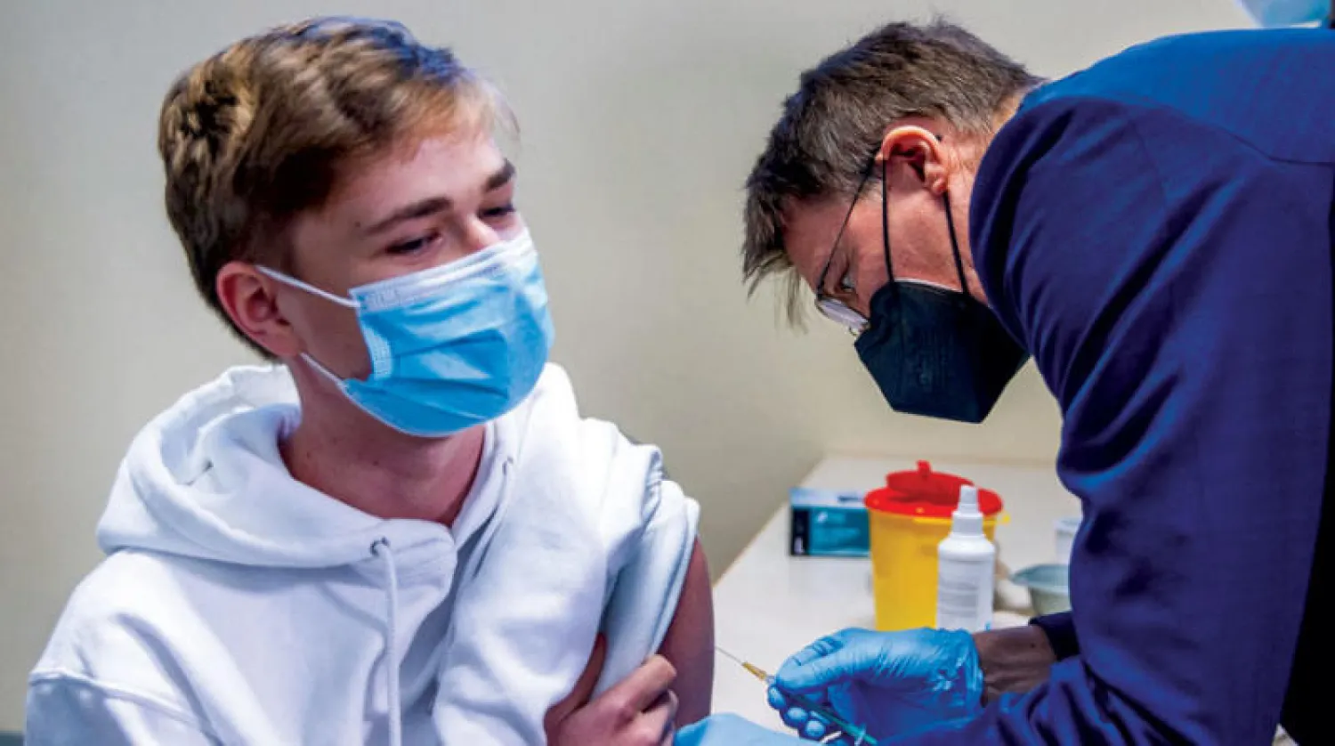 وزير الصحة الألماني كارل لاوترباخ يعطي شاباً لقاح «فايزر» بأحد مراكز التطعيم (أ.ف.ب)