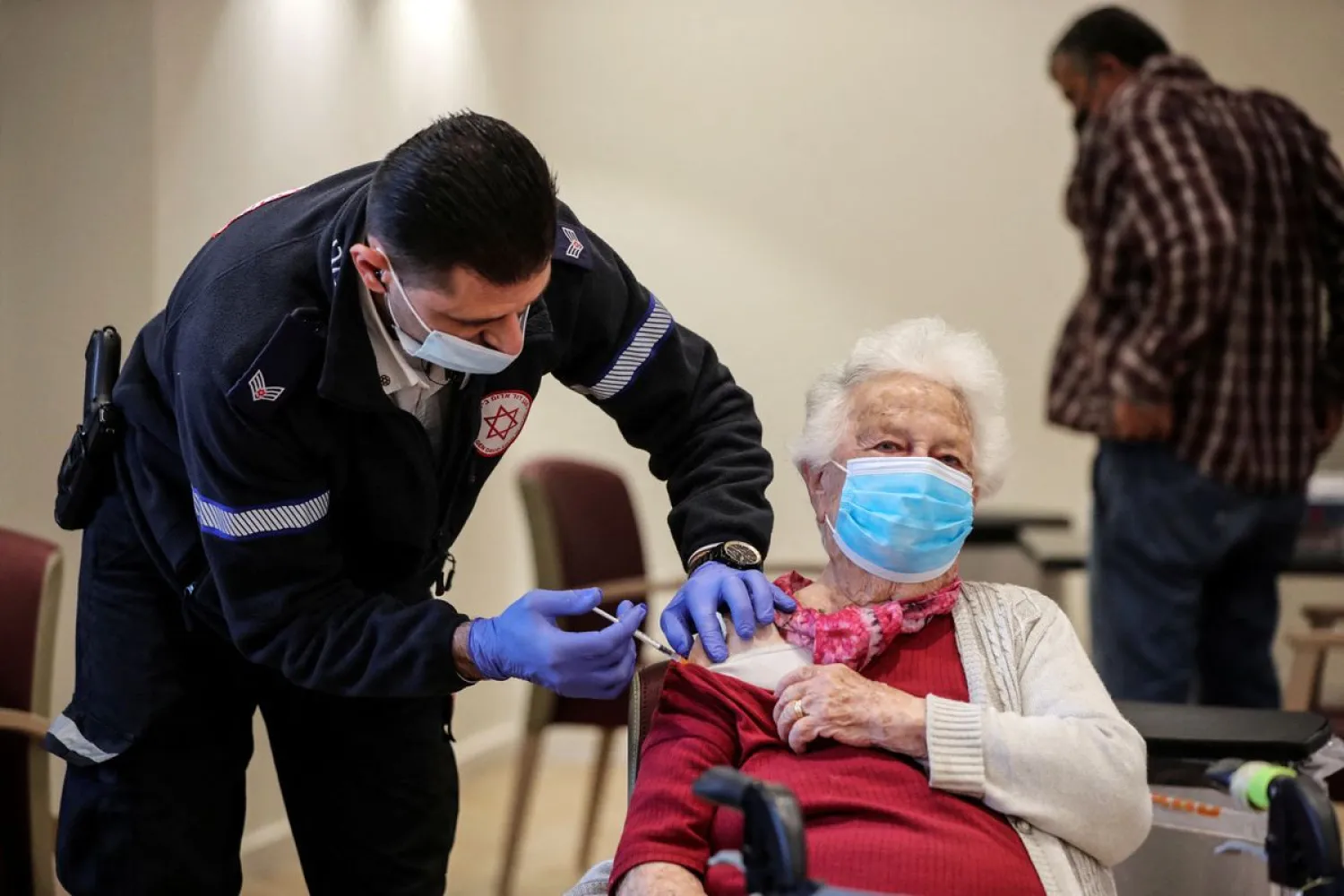 93-year-old Shari Marco receives a fourth dose of the coronavirus disease (COVID-19) vaccine following a vaccination party after Israel approved a second booster shot for the immuno-compromised, people over 60 years and medical staff in a retirement home in Netanya, Israel January 5, 2022. (Reuters)