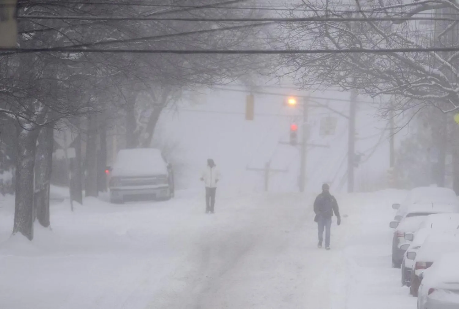 Pedestrians make their way down a partially plowed Murray Avenue Monday, Jan. 17, 2022, in Squirrel Hill neighborhood of Pittsburgh. (Pam Panchak/Pittsburgh Post-Gazette via AP)
