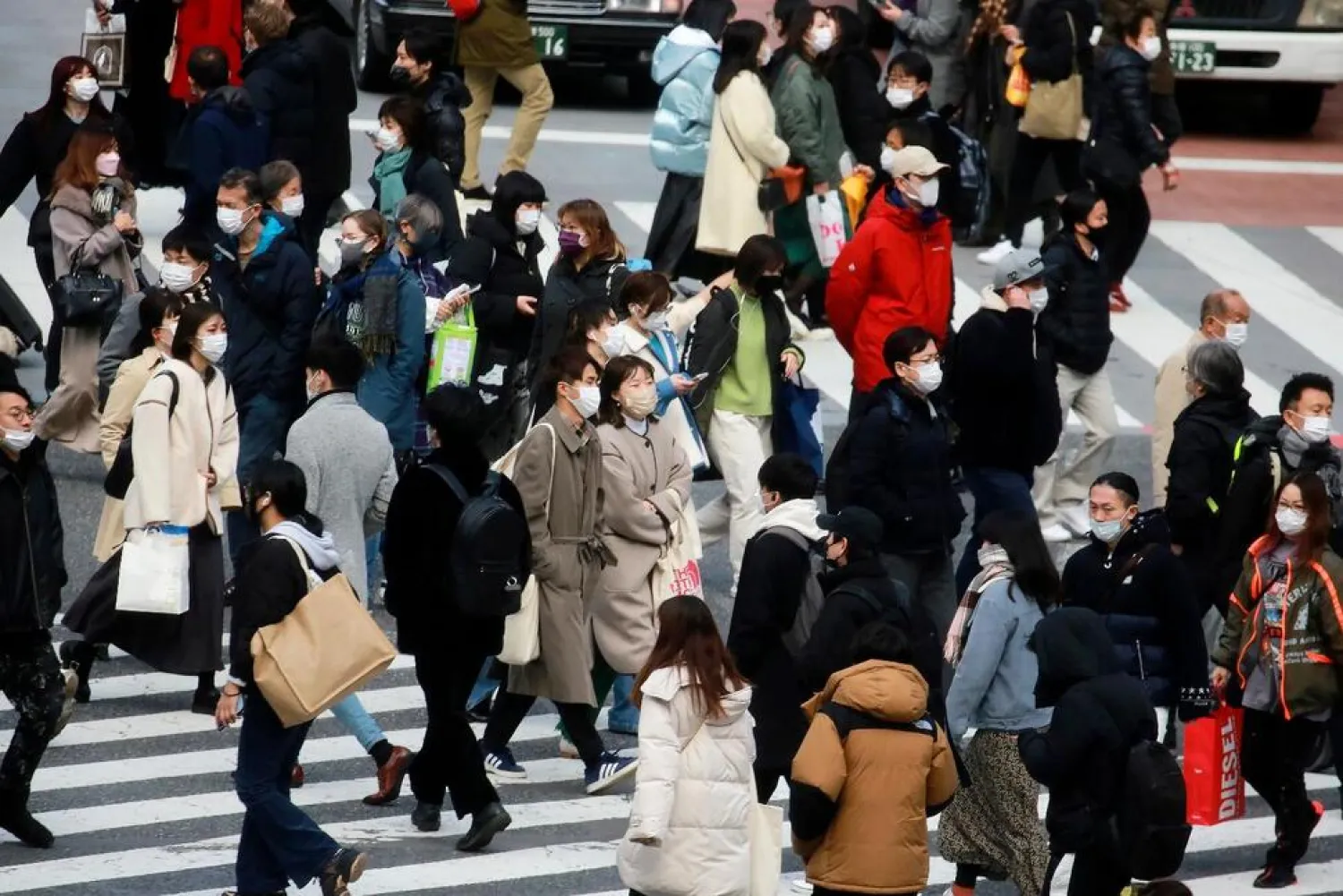 People wearing face masks to help protect against the spread of the coronavirus walk along the street in Tokyo, Wednesday, Jan. 19, 2022. (AP)