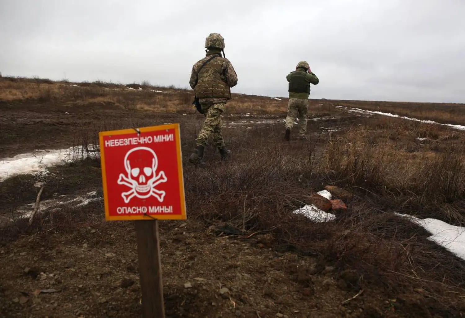 Ukrainian Military Forces servicemen walk past a metal plate which reads as "Caution mines" on the frontline with Russia-backed separatists near Luganske village, in Donetsk region on Jan. 11, 2022. (Anatolii Stepanov/AFP via Getty Images)
