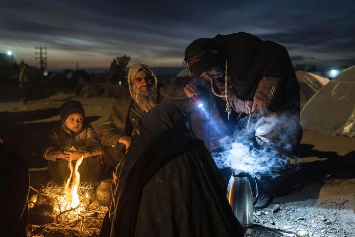 A family prepares tea outside the Directorate of Disaster office where they are camped, in Herat, Afghanistan, on Nov. 29, 2021. (AP)