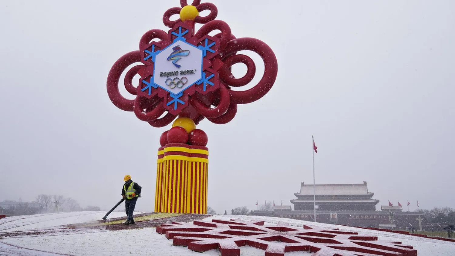 FILE - A worker wearing a face mask to protect from the coronavirus uses a blower to clean the snow on a decoration for the Beijing Winter Olympics Games on display at Tiananmen Square in Beijing, Jan. 20, 2022.(Andy Wong | AP Photo/Andy Wong, File)
