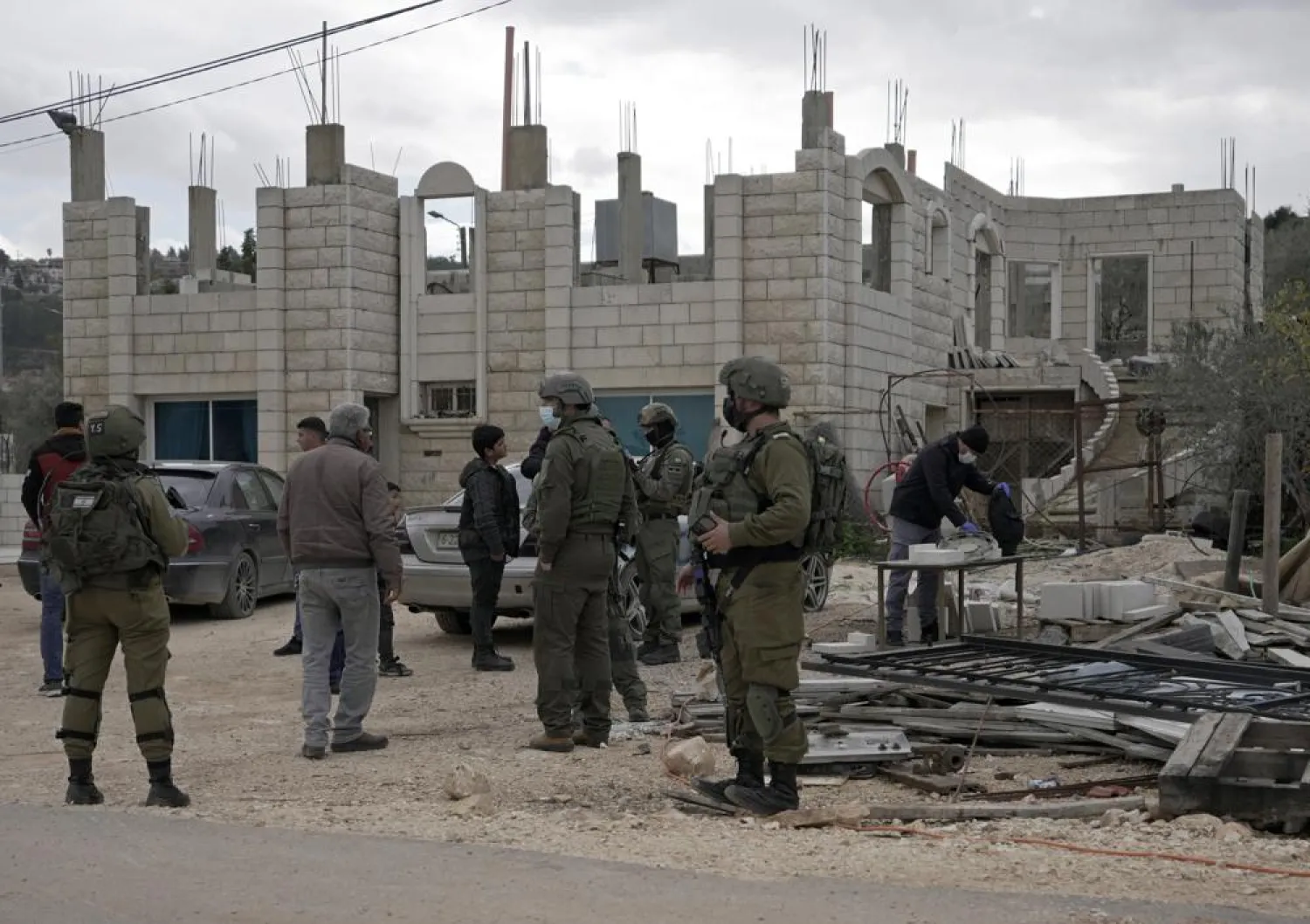 Israeli soldiers stand next to cars that the Palestinian owners said had their tires slashed and were spray painted with the Star of David and Hebrew by Jewish settlers, in the village of Qira near the West Bank town of Salfit, Sunday, Jan 23, 2022. (AP Photo/Majdi Mohammed)

