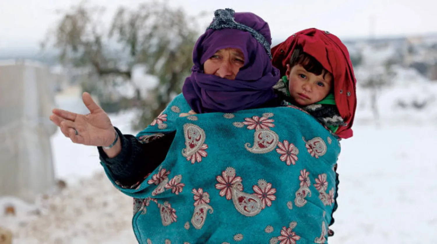 امرأة تحمل طفلاً بمخيم «أعزاز» بريف حلب شمال سوريا في 23 الشهر الجاري (أ.ف.ب)