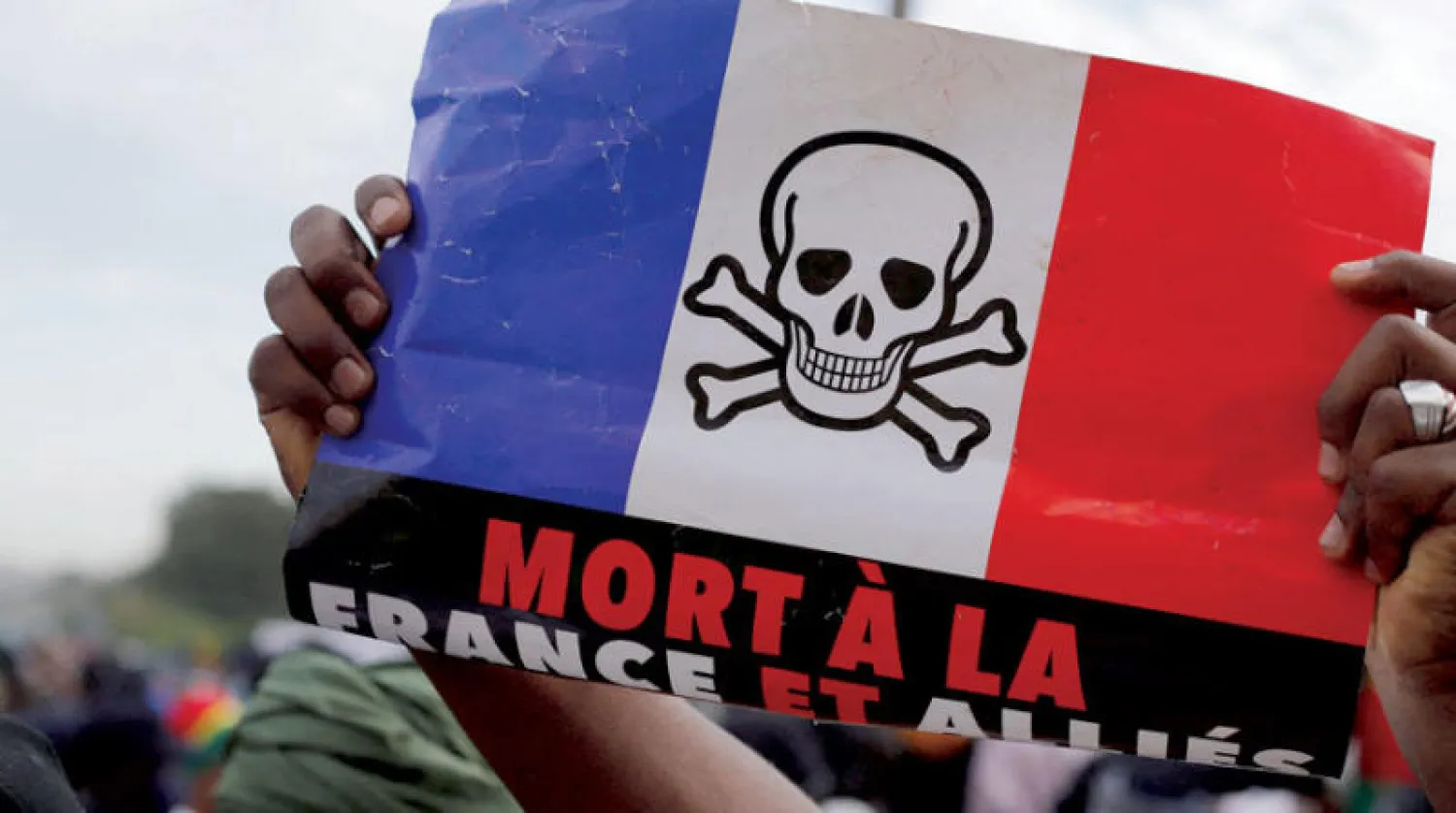 مؤيدون للحكومة الانتقالية في مالي يتظاهرون ضد الوجود الفرنسي في مالي يرفعون علماً فرنسياً كُتب عليه «الموت لفرنسا» (رويترز)