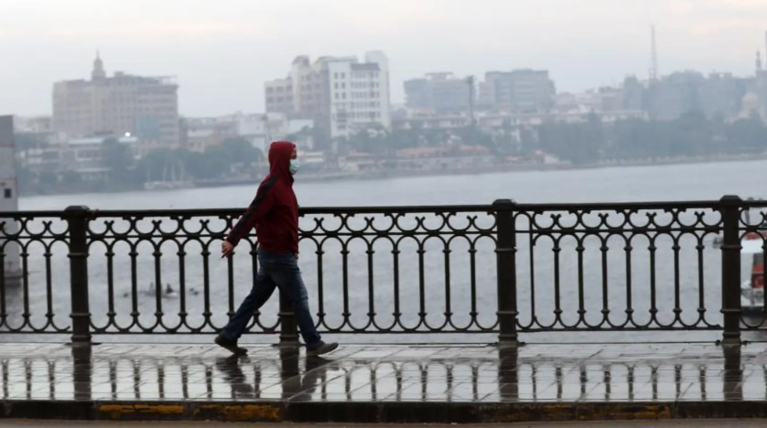 Kahire'de şiddetli yağmur sonrası bir işçi üstünü örterken (AP)