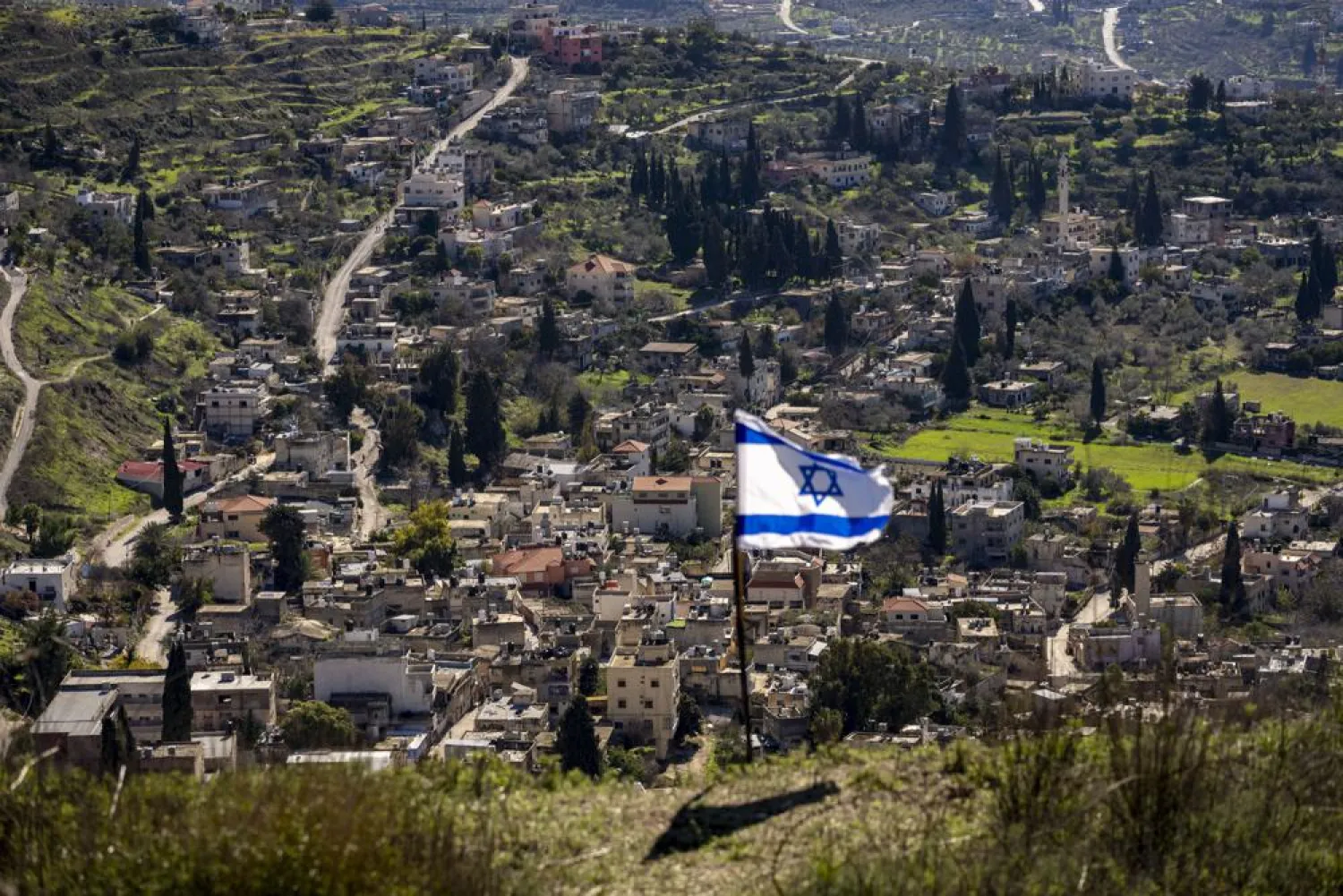The Palestinian village of Burqa is seen as an Israeli flag is placed in the Jewish West Bank outpost of Homesh, Monday, Jan. 17, 2022.
 (AP Photo/Ariel Schalit)
