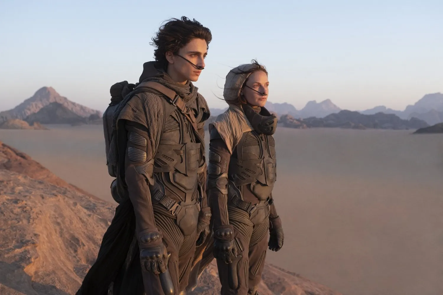 Timothee Chalamet (L), and Rebecca Ferguson look off into the distance, in a scene from the film "Dune." (Warner Bros. via AP)