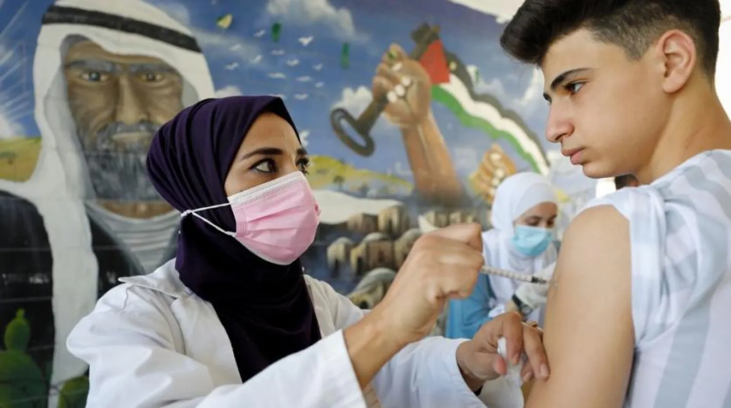 A Palestinian student receives a dose of Pfizer coronavirus disease (COVID-19) vaccine as a school year begins, in a school near Hebron in the Israeli-occupied West Bank, September 1, 2021. (Reuters)