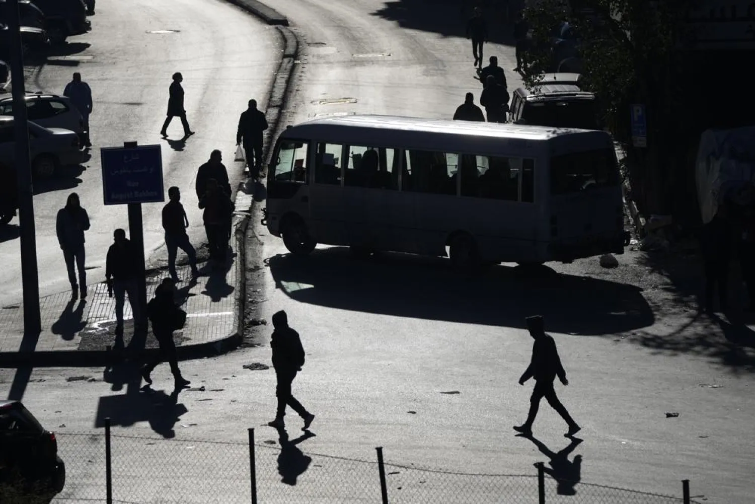 People are silhouetted on the streets as vehicles block a main roadway during a general strike by public transport unions protesting the country's deteriorating economic and financial conditions in Beirut, Lebanon, Wednesday, Feb. 2, 2022. (AP Photo/Hassan Ammar)
