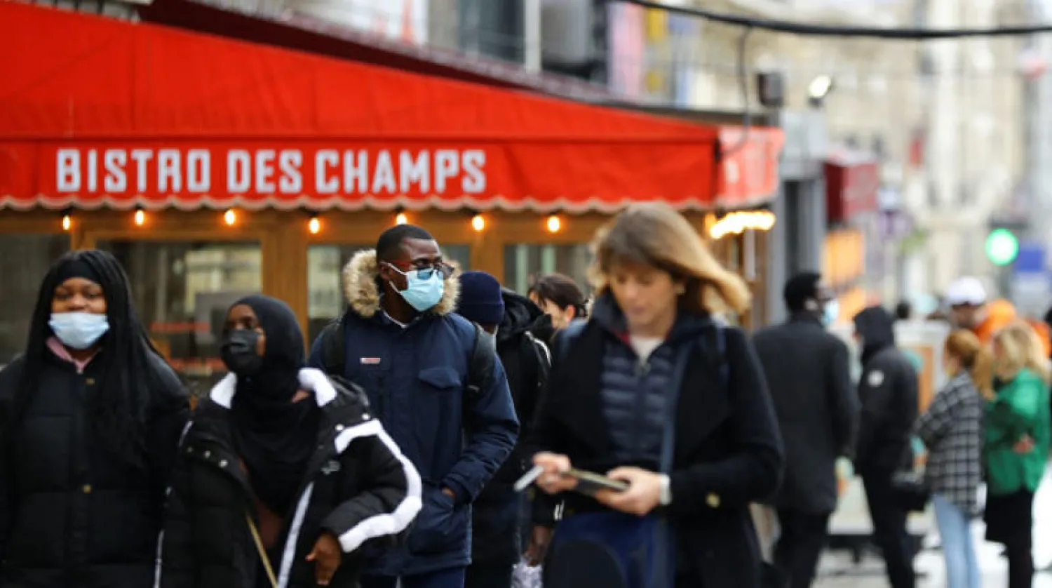 أشخاص يلتزمون ارتداء الكمامات في أحد شوارع باريس (رويترز)