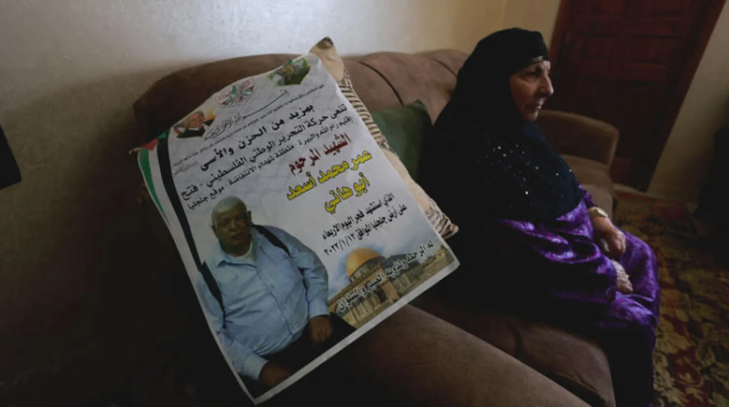 زوجة المسنّ عمر أسعد ضحية كتيبة {خلود اليهود} قرب ملصق نعيه في منزلها برام الله (رويترز)