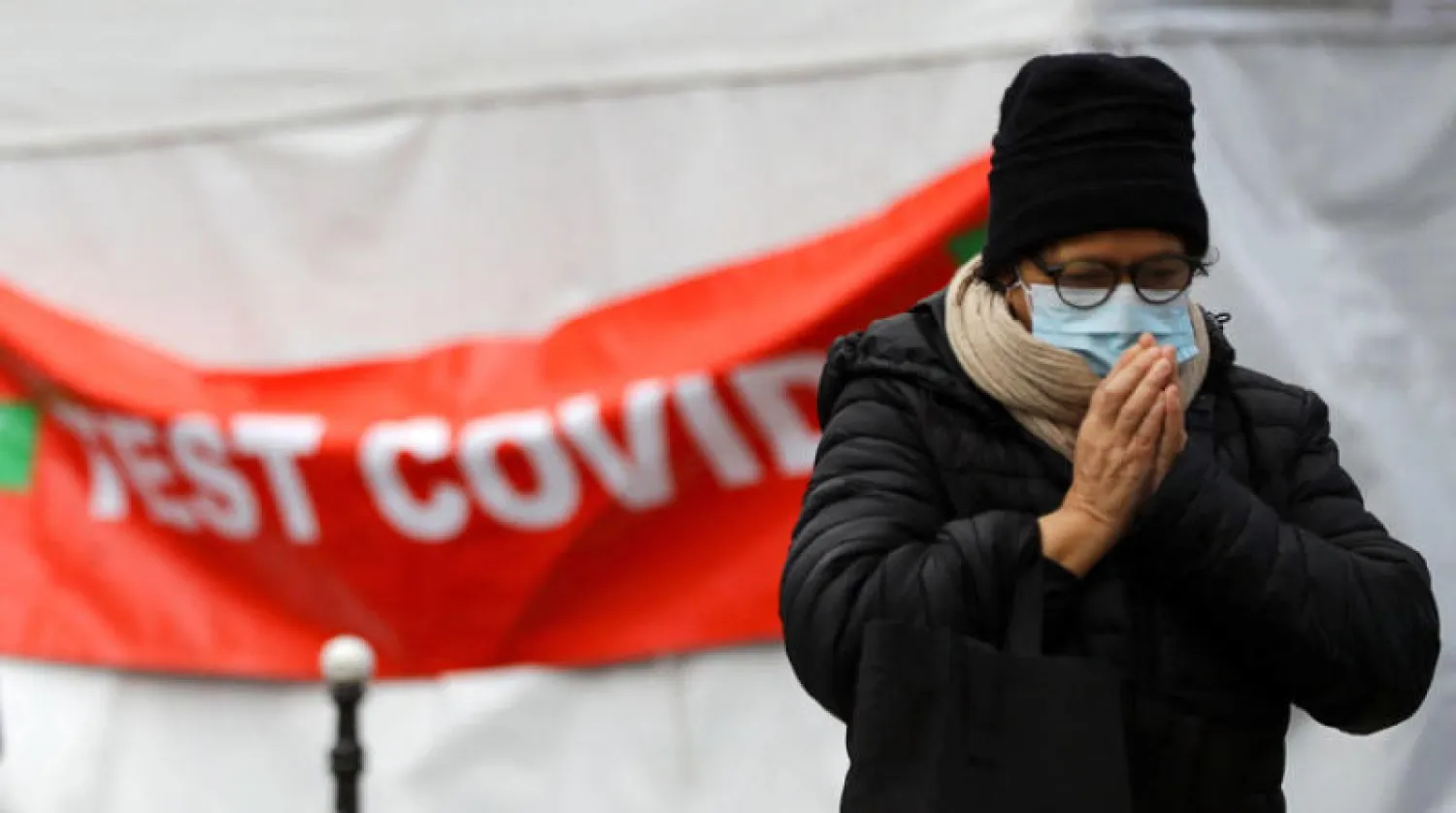 سيدة ترتدي كمامة وهي تمر بالقرب من مركز فحص متنقل في باريس أمس (رويترز)