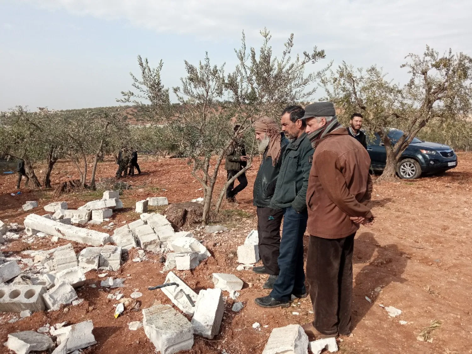 شهود عيان يقفون في ساحة منزل قرب بلدة أطمة وسط حطام أحد المنازل (الشرق الأوسط)