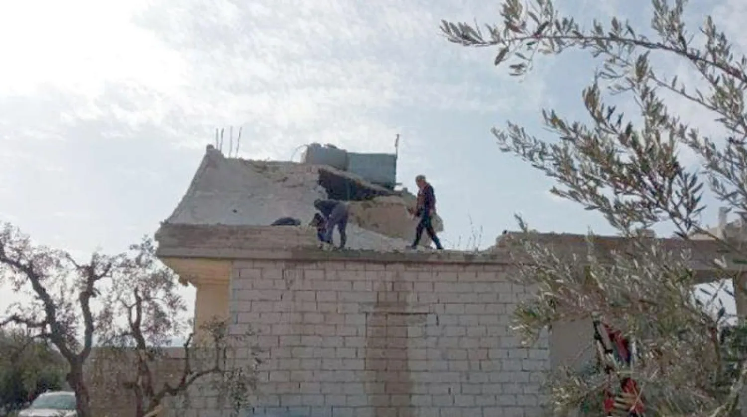 رجلان أعلى المنزل الذي كان فيه زعيم «داعش» بريف إدلب (الشرق الأوسط)
