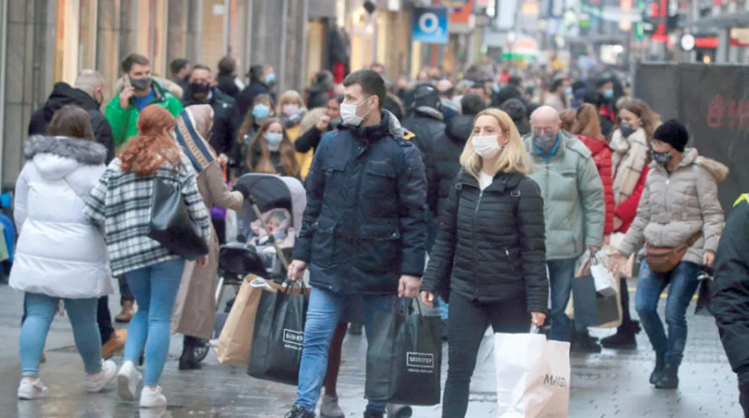 متسوقون يلتزمون بالكمامات في أحد شوارع كولونيا الألمانية في 12 ديسمبر الماضي (رويترز)