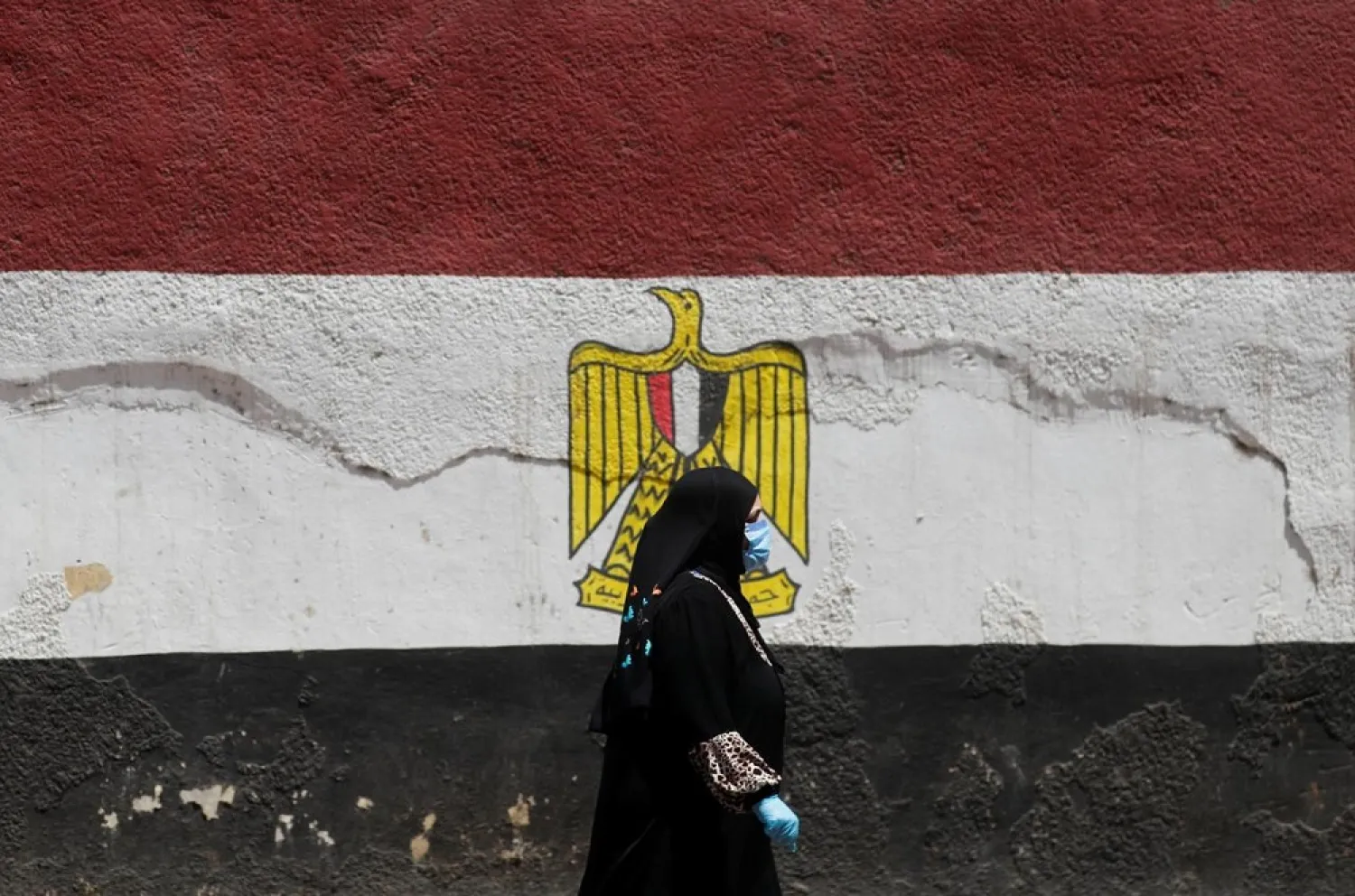 A woman wearing a protective face mask, amid concerns over the coronavirus, walks next to a wall painted with colors of the Egypt's flag in Cairo, Egypt April 26, 2020. (Reuters)