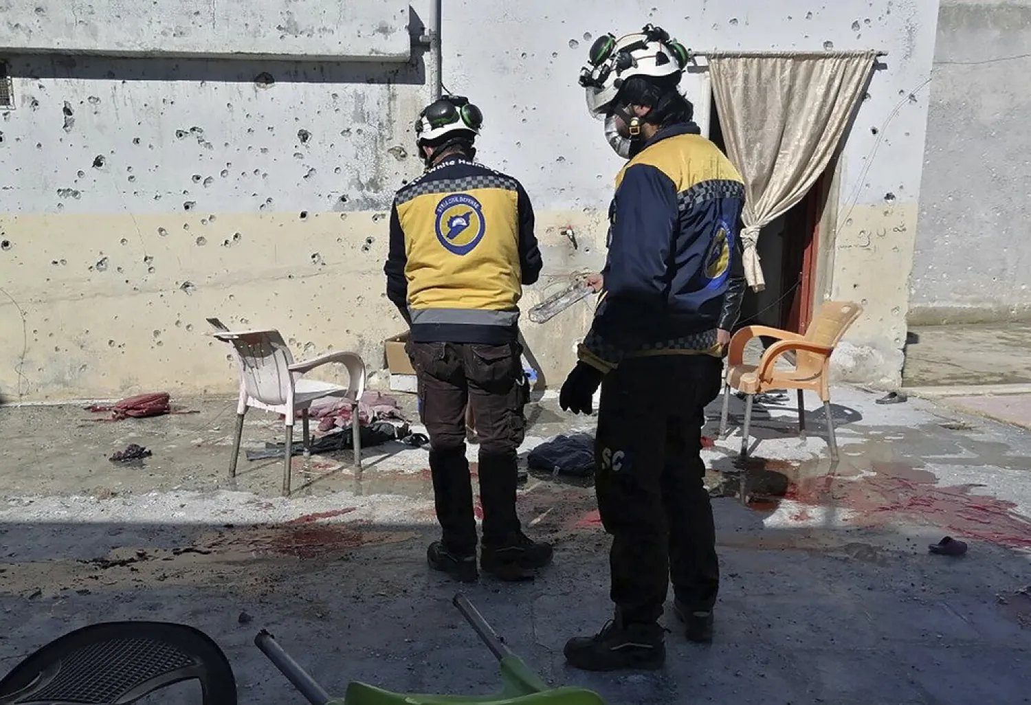 In this photo provided by the Syrian Civil Defense White Helmets, which has been authenticated based on its contents and other AP reporting, Syrian White Helmet civil defense workers stand at the site where a shell struck in the Maaret al-Naasan village in Idlib province, Syria, Saturday, Feb. 12, 2022. (Syrian Civil Defense White Helmets via AP)