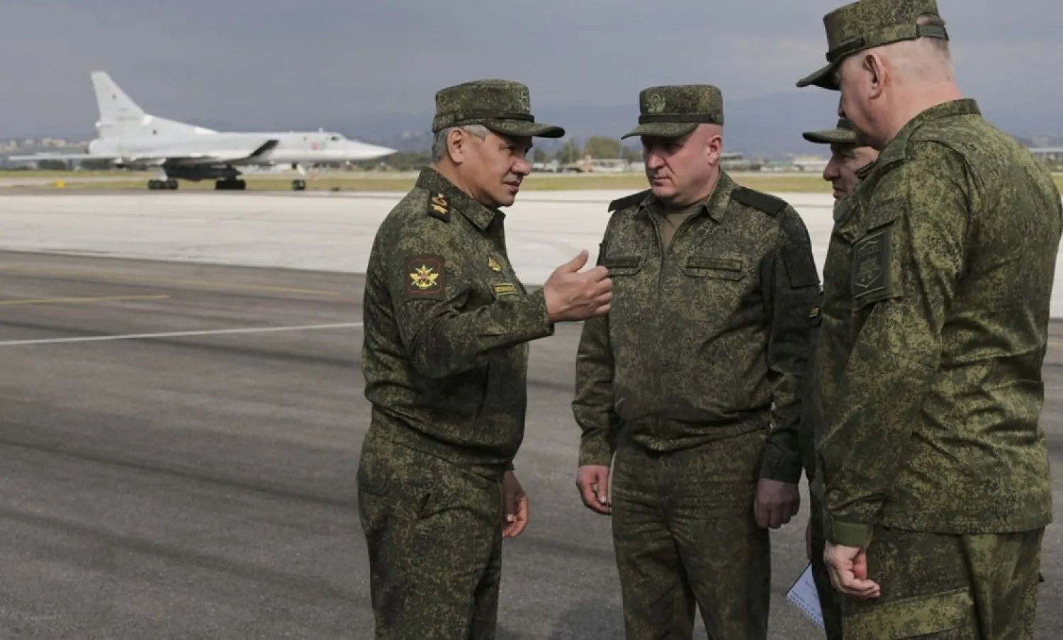 In this photo taken from video provided by the Russian Defense Ministry Press Service on Tuesday, Feb. 15, 2022, Russian Russian Defense Minister Sergei Shoigu, left, speaks to a group of officers as a Tu-22M3 bomber of the Russian air forces is seen parked at the Hmeimim air base in Syria. (Russian Defense Ministry Press Service via AP)