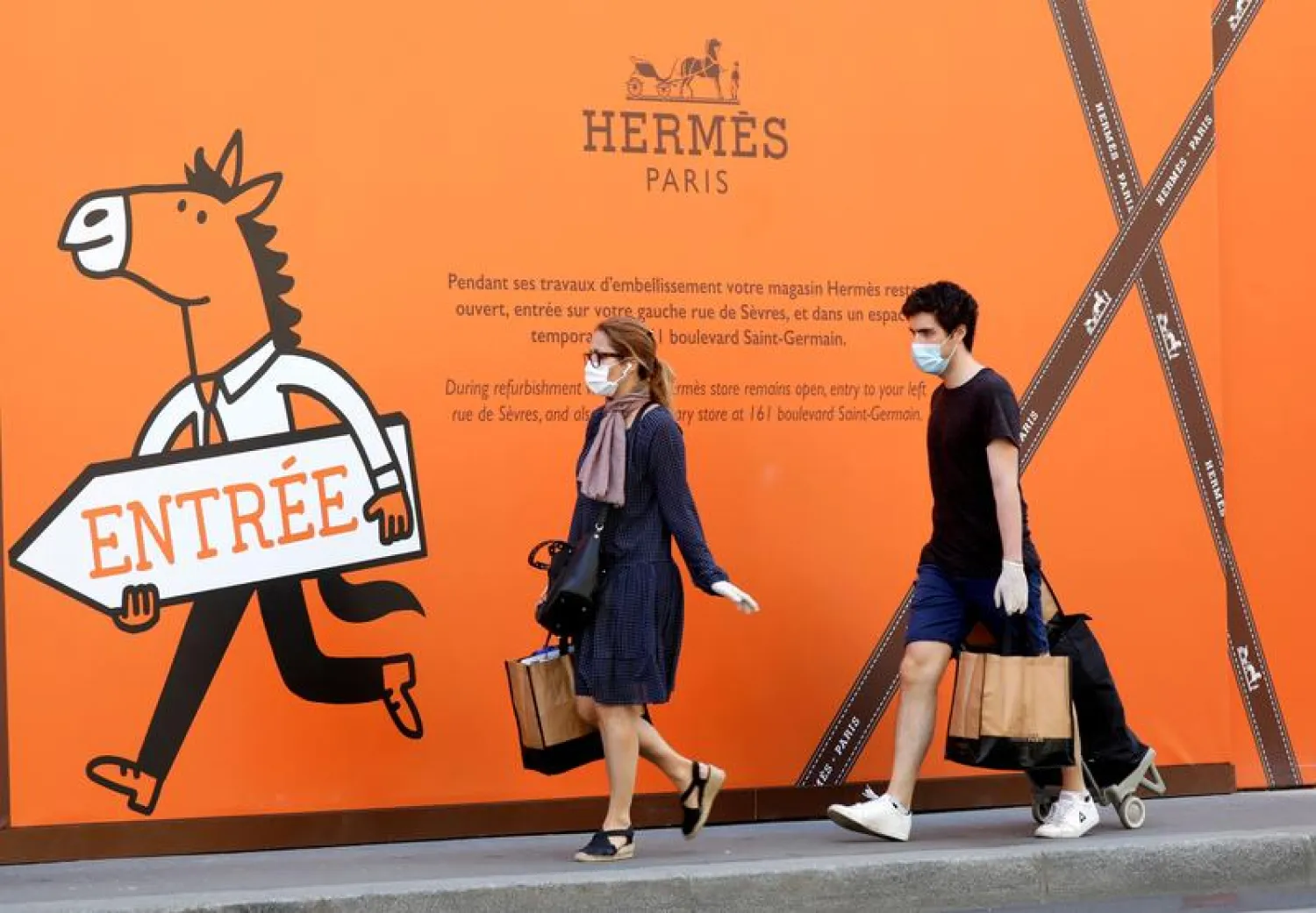 Residents, wearing protective face masks, walk past a Hermes store in Paris, France, April 24, 2020. (Reuters)