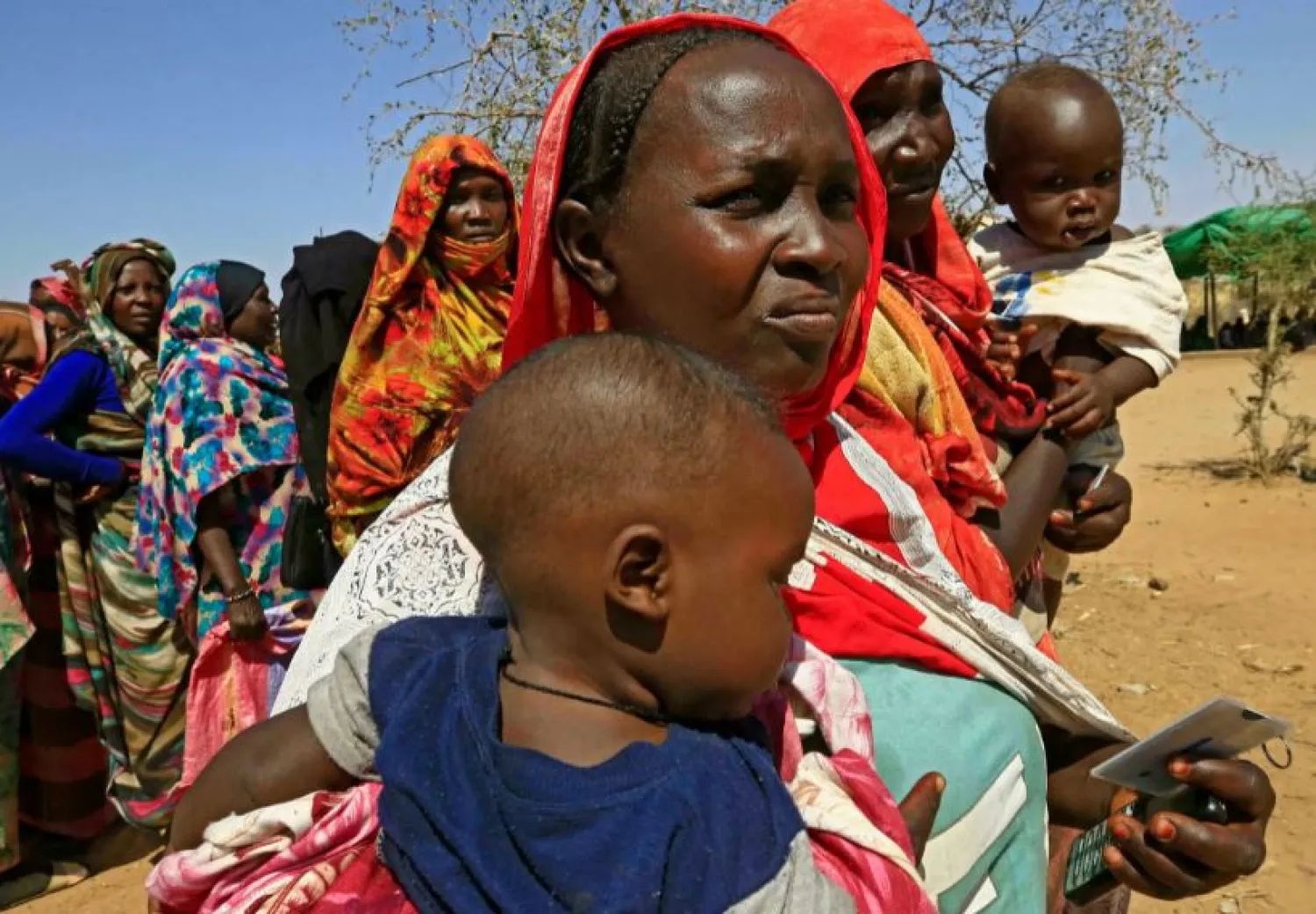 Sudanese women wait on February 1, 2021 for World Food Program (WFP) aid trucks in Darfur's Otash camp for internally displaced people ASHRAF SHAZLY AFP/File
