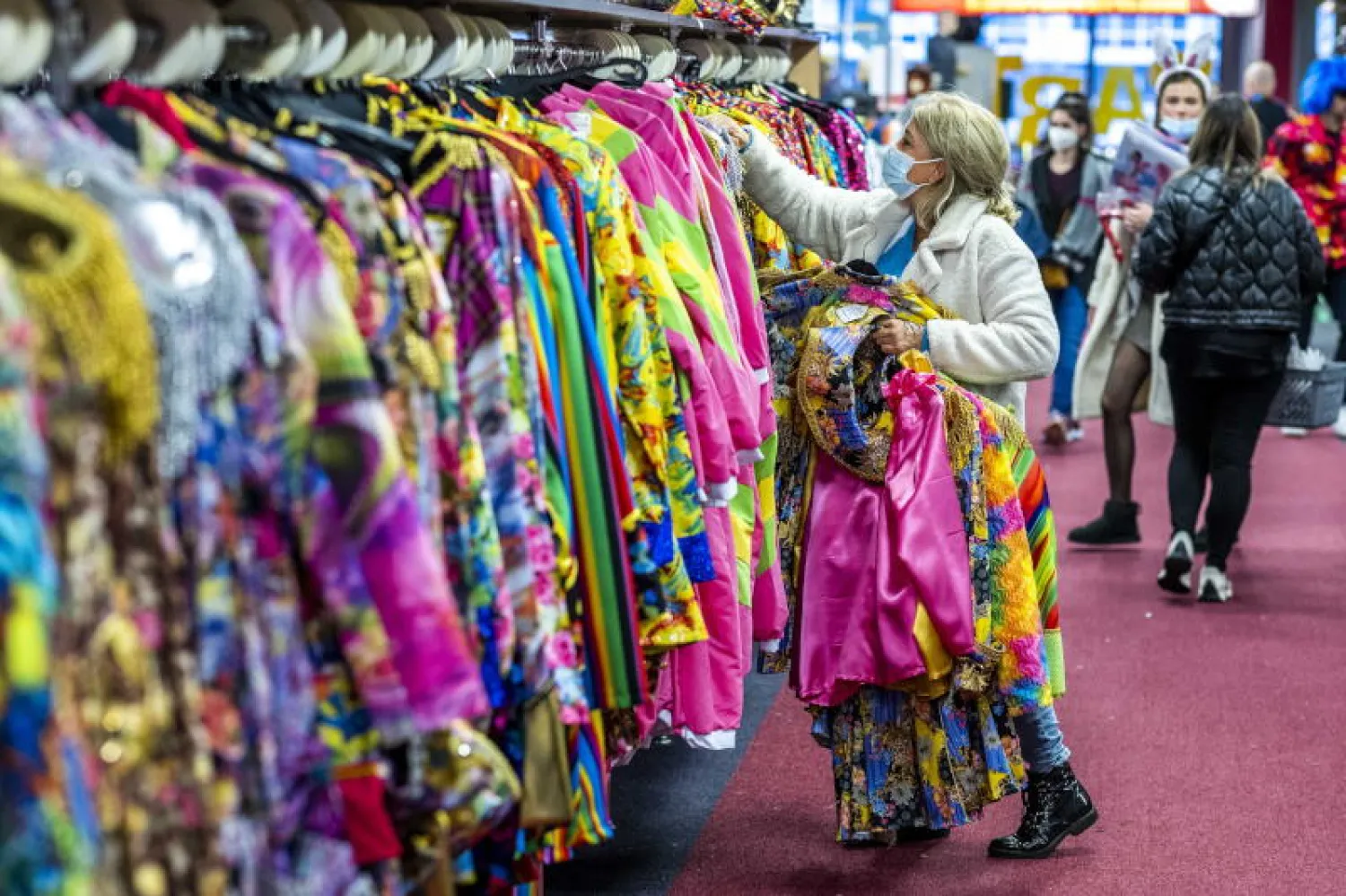 متسوقات يضعن كمامات بمتجر للثياب في مدينة هيرلن الهولندية (إ.ب.أ)