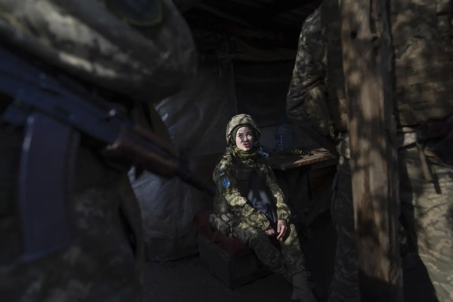 A Ukrainian soldier talks with her comrades sitting in a shelter at the line of separation between Ukraine-held territory and rebel-held territory near Svitlodarsk, eastern Ukraine, Wednesday, Feb. 23, 2022. (AP Photo/Evgeniy Maloletka)

