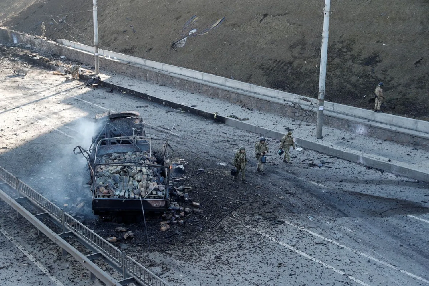 Ukrainian servicemen walk by a damaged vehicle, at the site of fighting with Russian troops, after Russia launched a massive military operation against Ukraine, in Kyiv, Ukraine February 26, 2022. (Reuters)