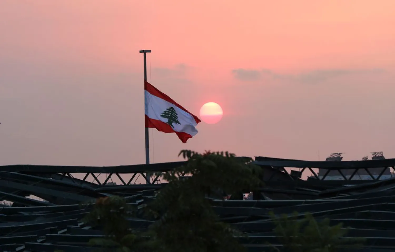 Lebanese flag flutters at the site of last year's Beirut port blast, during sunset in Beirut, Lebanon, July 29, 2021. Picture taken July 29, 2021. (Reuters)