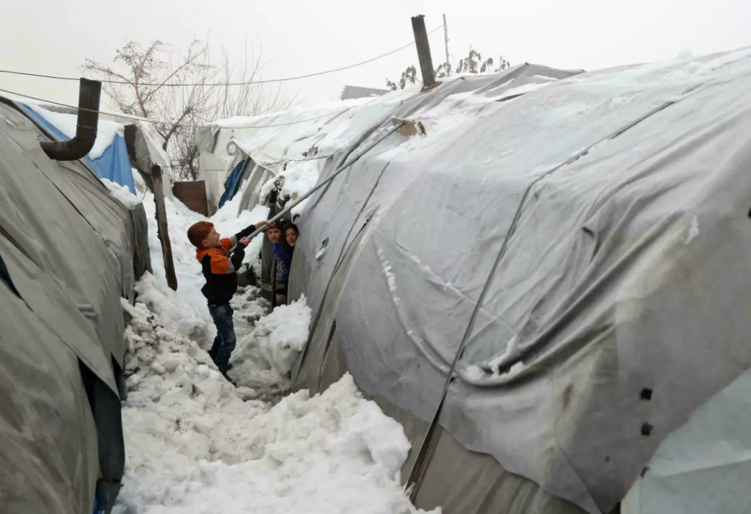 A boy clears snow from a tent at a Syrian camp for the internally displaced near the city of Jisr al-Shughur in the northwestern province of Idlib, on January 26, 2022 OMAR HAJ KADOUR AFP/File