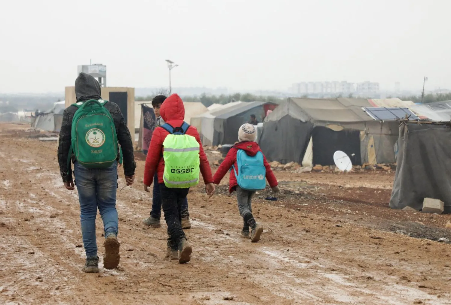 Internally displaced Syrians walk together near tents at a camp in Azaz, Syria March 1, 2022. Picture taken March 1, 2022. (Reuters)